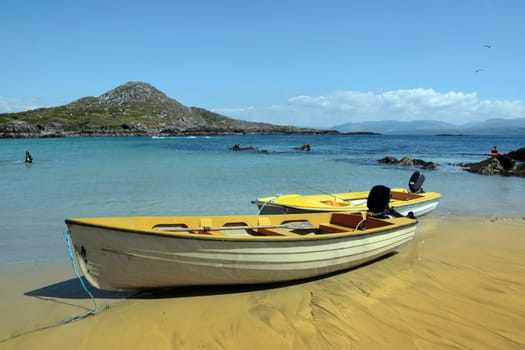 yellow boats moored at a sandy beach on the coast of county kerry ireland