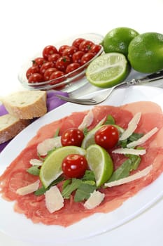 a plate of carpaccio with parmesan,lime and arugula