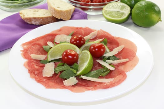 a plate of carpaccio with parmesan,lime and arugula