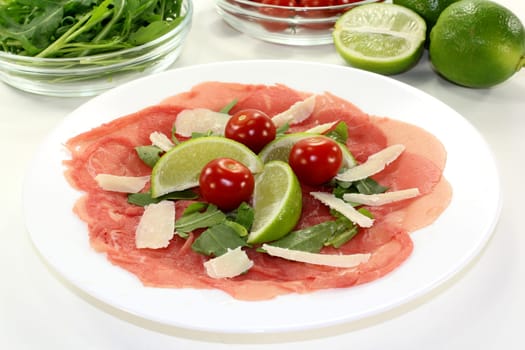a plate of carpaccio with parmesan,lime and arugula