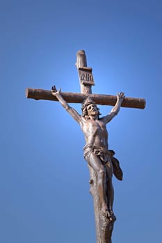 Statue of Jesus Christ on a cross. Blue sky in the background.
