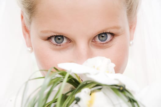 Blonde bride with very beautiful eyes with veil and bridal bouquet
