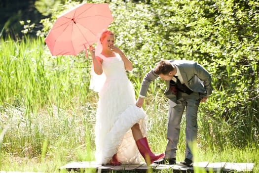 Bride and groom with umbrella and rubber boots