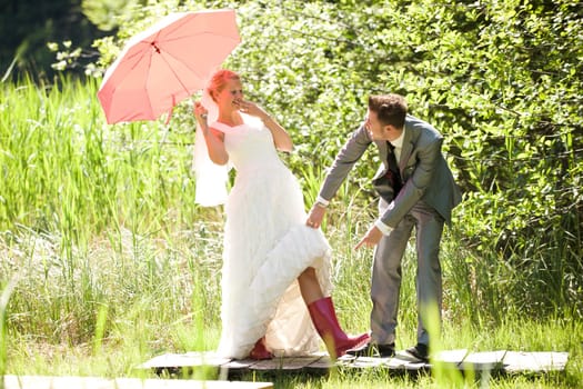 Bride and groom with umbrella and rubber boots