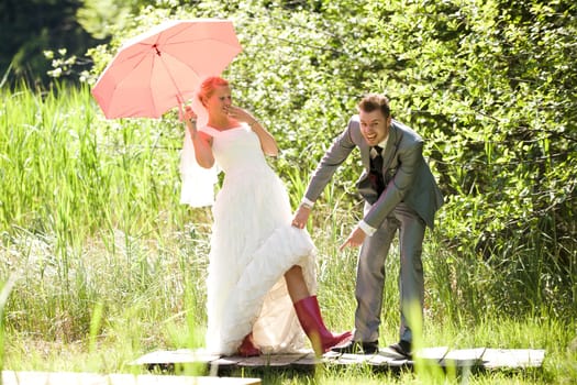 Bride and groom with umbrella and rubber boots