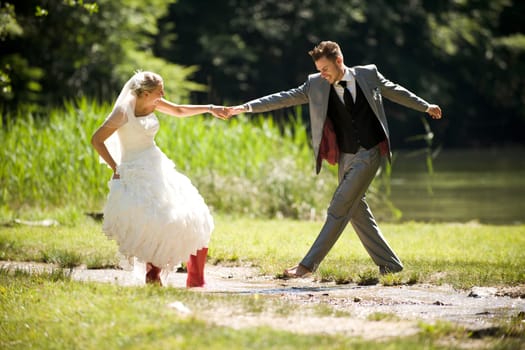 Bride and groom in river splashing wet and having fun