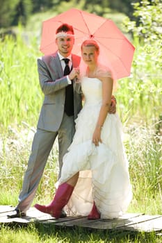 Bride and groom with umbrella and rubber boots