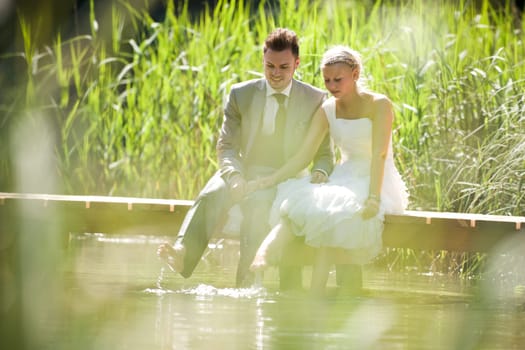 Bride and groom sitting romantically by a lake
