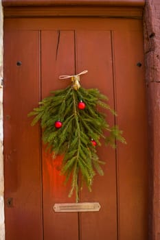 Christmas tree branches and balls decorate the vintage door