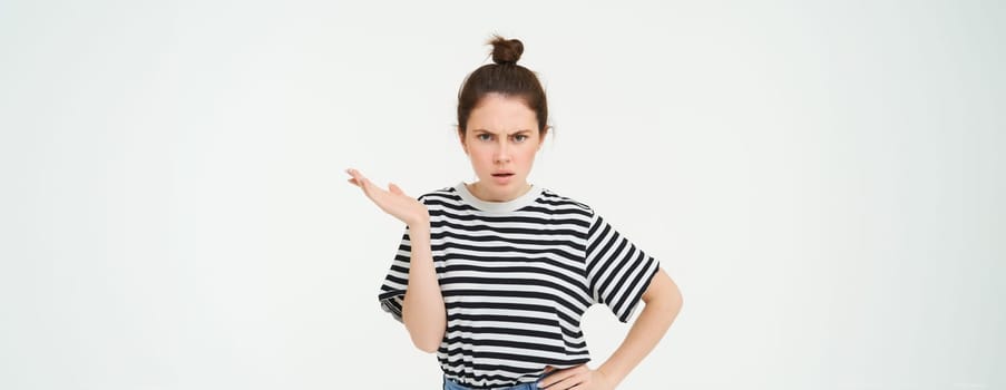 Image of frustrated woman complaining, looking puzzled, shrugging and frowning, standing over white background.