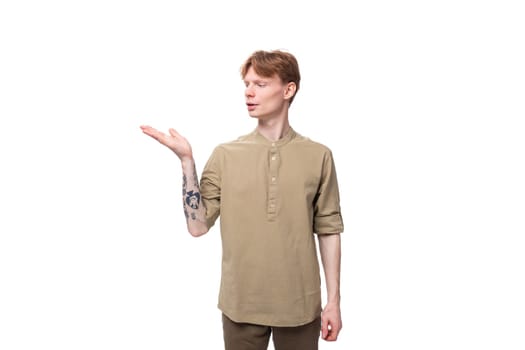 a young European man with red golden hair dressed in a light brown shirt gesticulates on a white background. advertising concept.