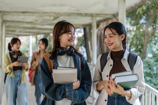 university students holding book and talking while walking to next class.