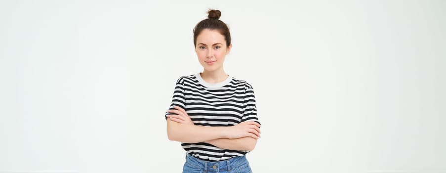 Portrait of young stylish woman, 25 years old, looking upbeat and motivated, posing for photo against white background.
