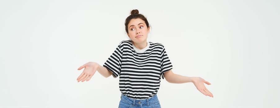 Image of confused brunette girl shrugging shoulders, looks puzzled, isolated over white background.