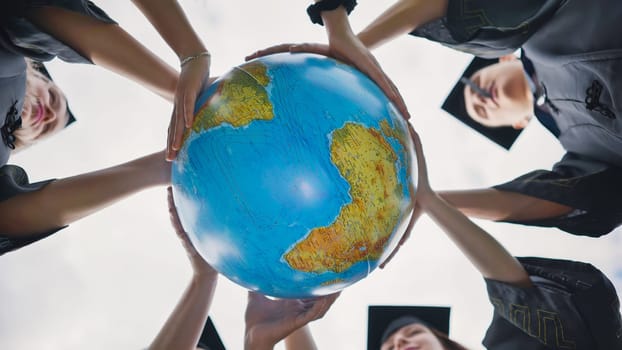 Graduating students twirl a geographic globe of the world in their hands