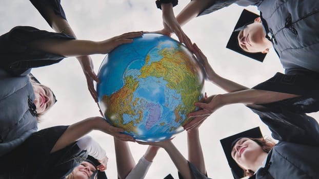 Graduating students twirl and toss a geographical globe of the world
