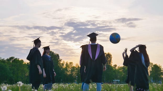 Graduates in costume playing with a ball at sunset