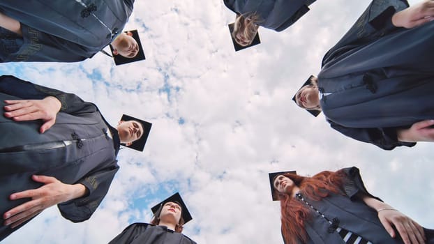 Graduates in black robes stand in a circle