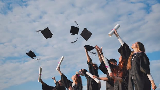 Graduating students hands throwing graduation caps in the air