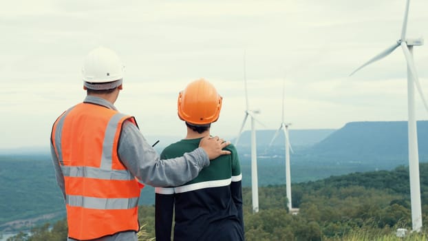 Engineer with his son on a wind farm atop a hill or mountain in the rural. Progressive ideal for the future production of renewable, sustainable energy. Energy generation from wind turbine.