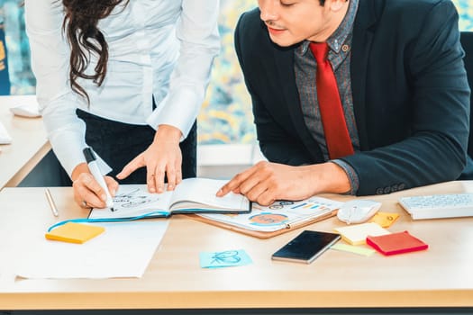 Two business people talk project strategy at office meeting room. Businessman discuss project planning with colleague at modern workplace while having conversation and advice on financial report. Jivy