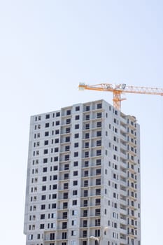 Tower crane and construction of a tall apartment building close up