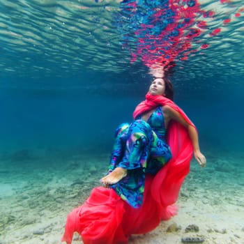 Young beautiful woman in blue dress underwater
