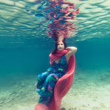 Young beautiful woman in blue dress underwater