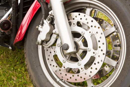 Bike chromed wheel on grassy background seems used