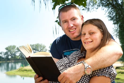 Guy and girl with books on the nature near lake