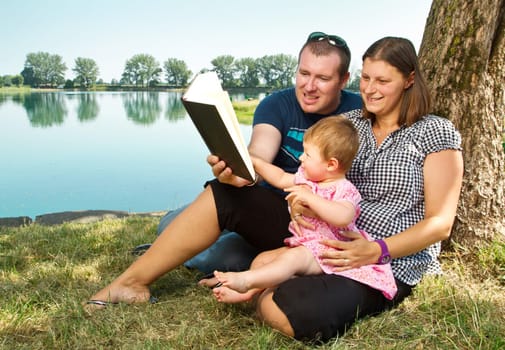 Guy and girl with books on the nature near lake