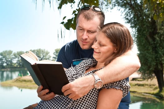 Guy and girl with books on the nature near lake