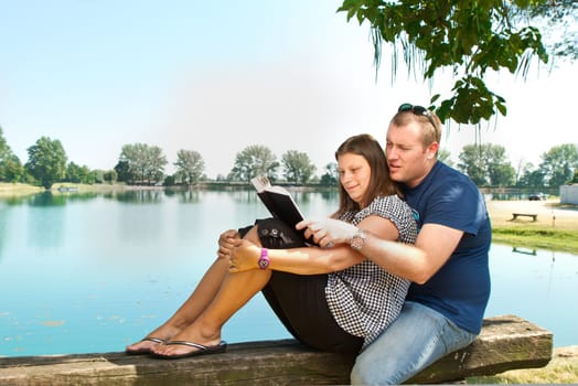 Guy and girl with books on the nature near lake