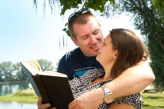 Guy and girl with books on the nature near lake