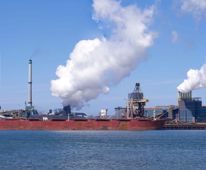 ship unloading in front of a large steel factory in IJmuiden, Netherlands