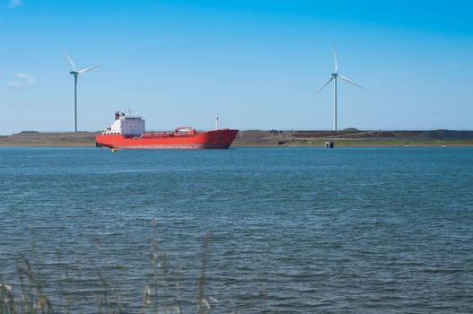 Red tanker entering the North Sea Canal at IJmuiden, Netherlands. It,s a man made ship canal from Amsterdam to the North Sea at IJmuiden, constructed between 1865 and 1876 to enable seafaring vessels to reach the port of Amsterdam.
