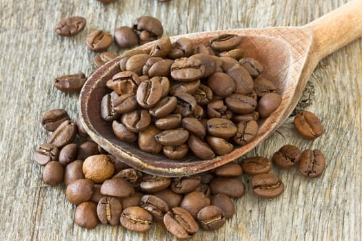 coffee beans with wooden spoon on wood background