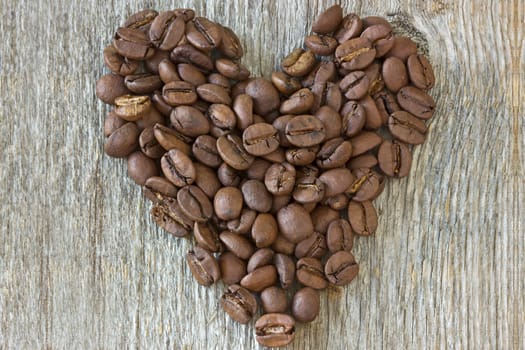 Heart made from coffee beans on wooden background