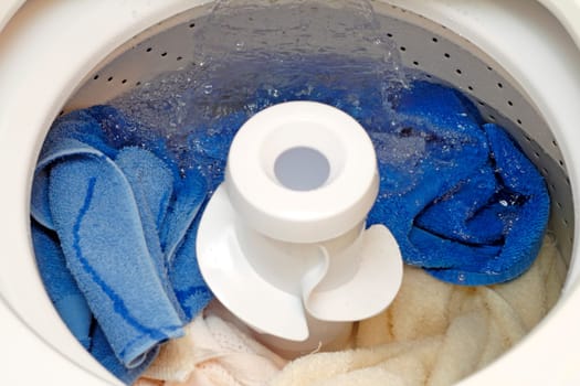 Washing machine being filled with water covering the full load of linens in order to do a wash.