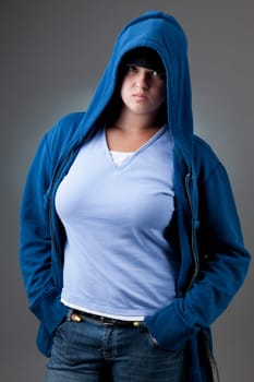 Studio portrait of a serious looking girl in a blue hooded jacket