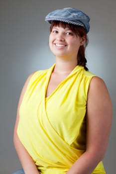 Portrait of a happy girl in yellow blouse and a denim cap