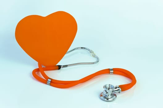 Stethoscope and big heart against light green background