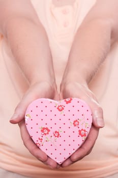 Woman holding a pink heart with flowers and both hands forward