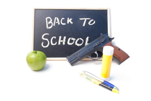 Pens, glue stick and an apple in front of a back to school written on a blackboard