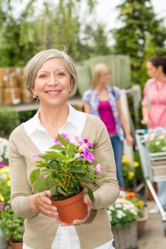 Senior lady shopping for flowers at garden centre smiling