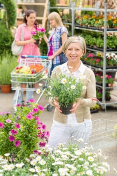 Senior lady shopping for flowers at garden centre smiling