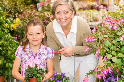 Senior woman with little girl shopping flowers at garden centre