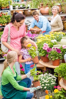 Little girl with parents picking flowers from garden shop