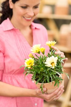 Portrait smiling woman hold yellow potted flowers in garden shop