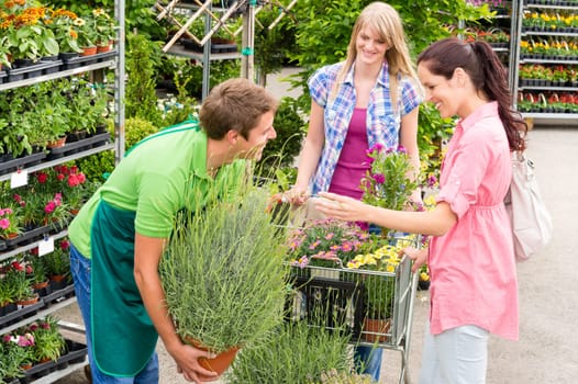 Male garden centre worker selling potted plant to female customers